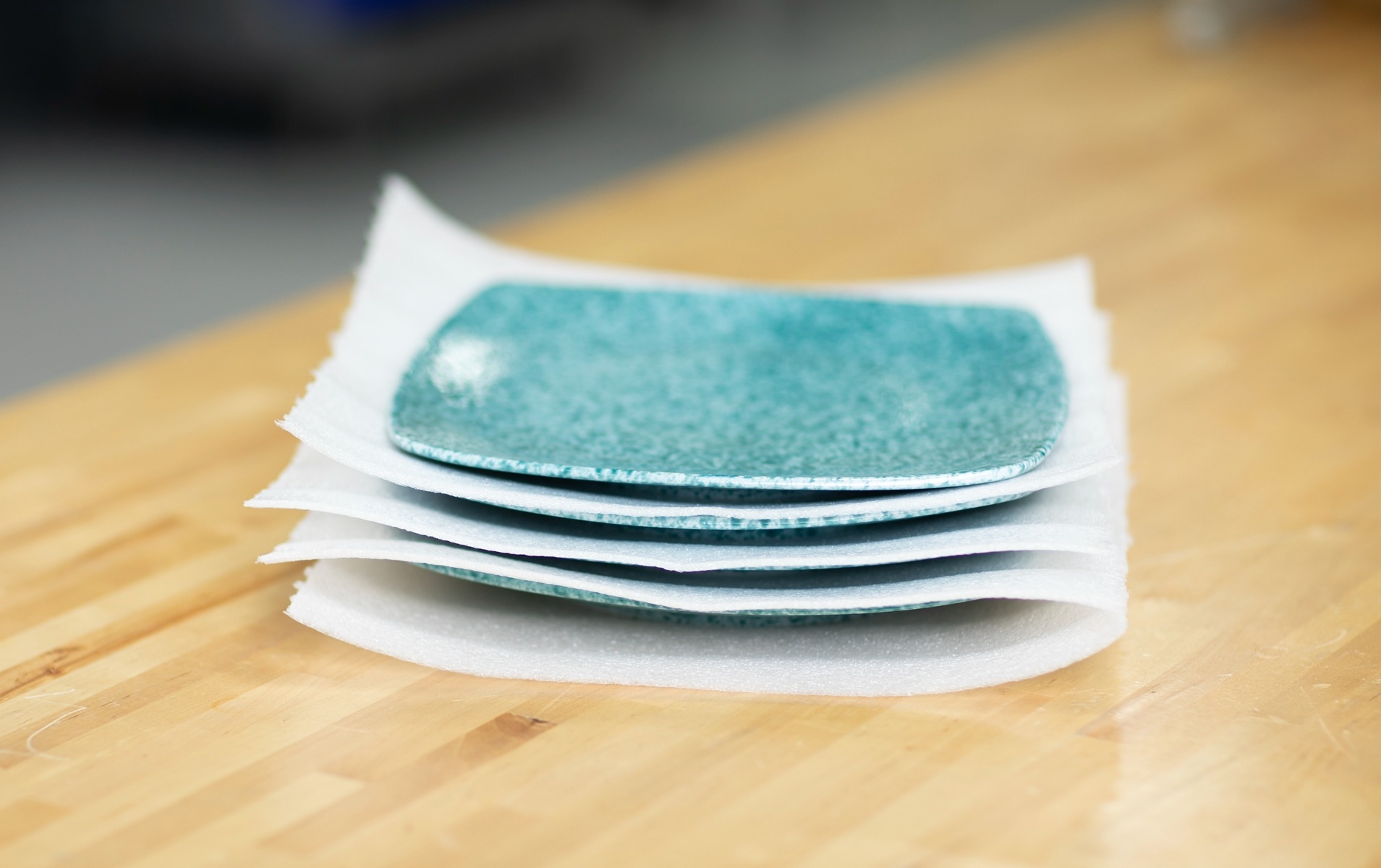 blue plates stacked on wood table with pregis foam sheets placed in between each plate